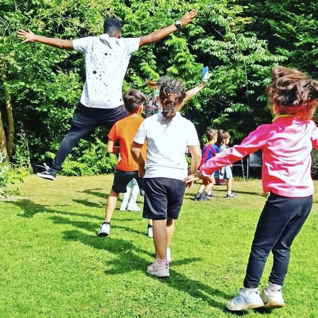 A line of children playing a game in a natural environment